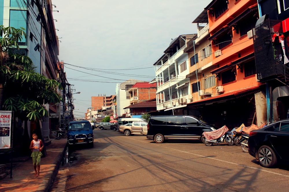 a woman walking down a street next to parked cars