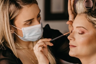 a woman getting her makeup done by another woman
