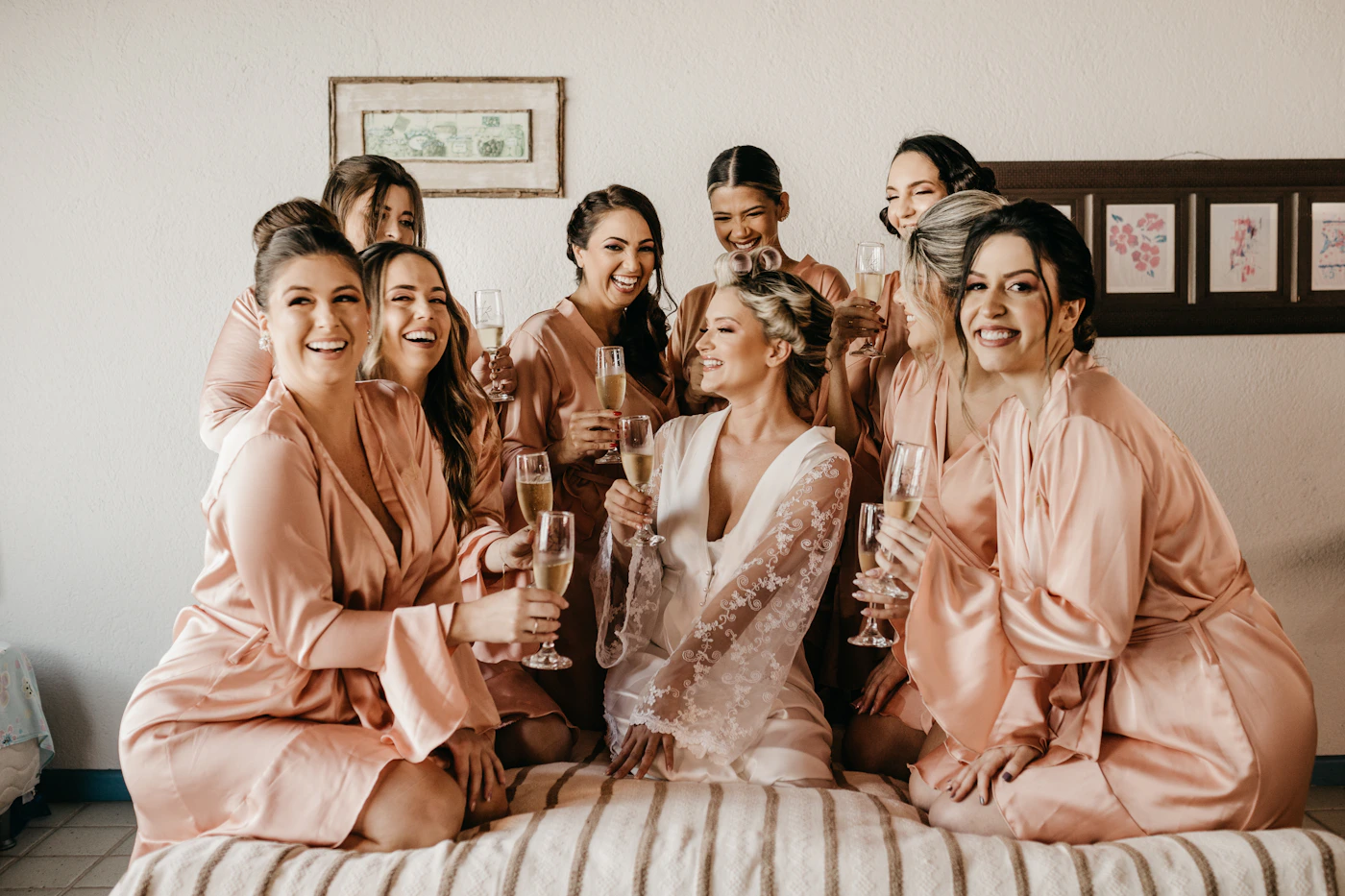 Group of women gathered together in a getting-ready setting for a wedding smiling and enjoying the morning preparation