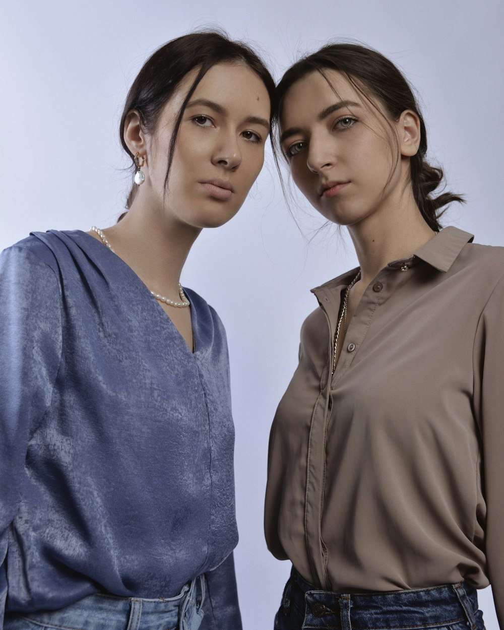 two women standing next to each other in front of a white background