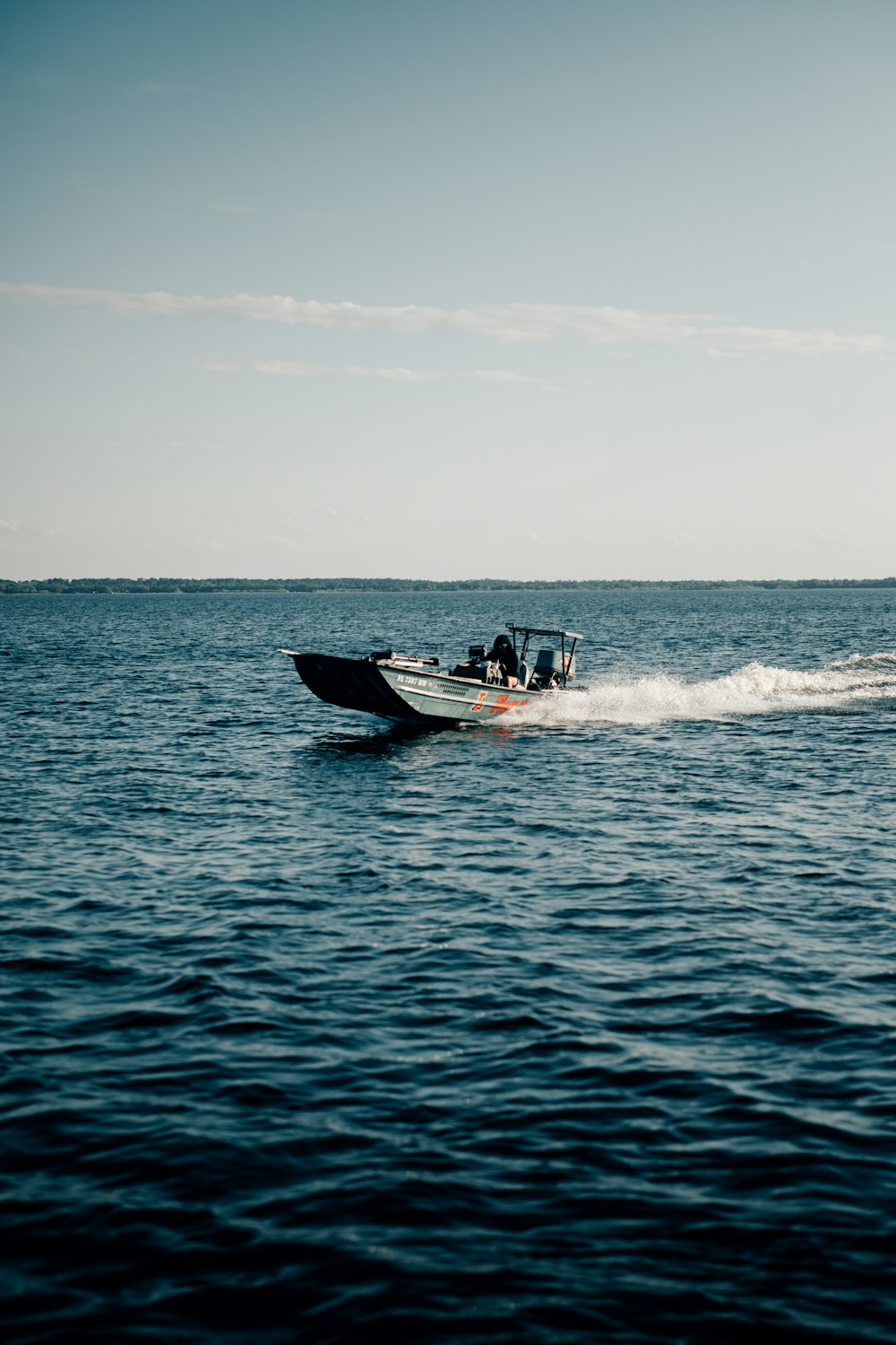 a speedboat speeding across the ocean on a sunny day