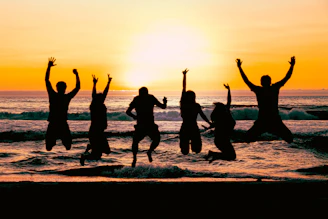 a group of people jumping in the air at the beach