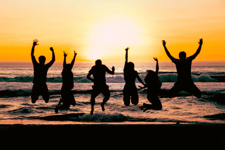 a group of people jumping in the air at the beach