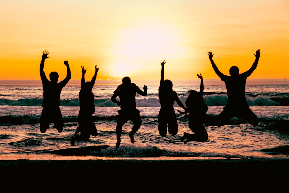 a group of people jumping in the air at the beach