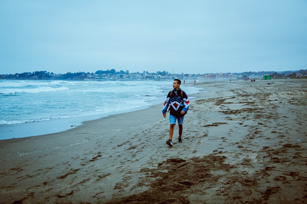 a man walking on a beach carrying a surfboard