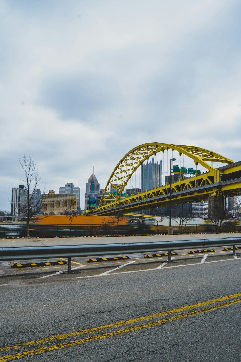 a yellow bridge over a highway with a city in the background