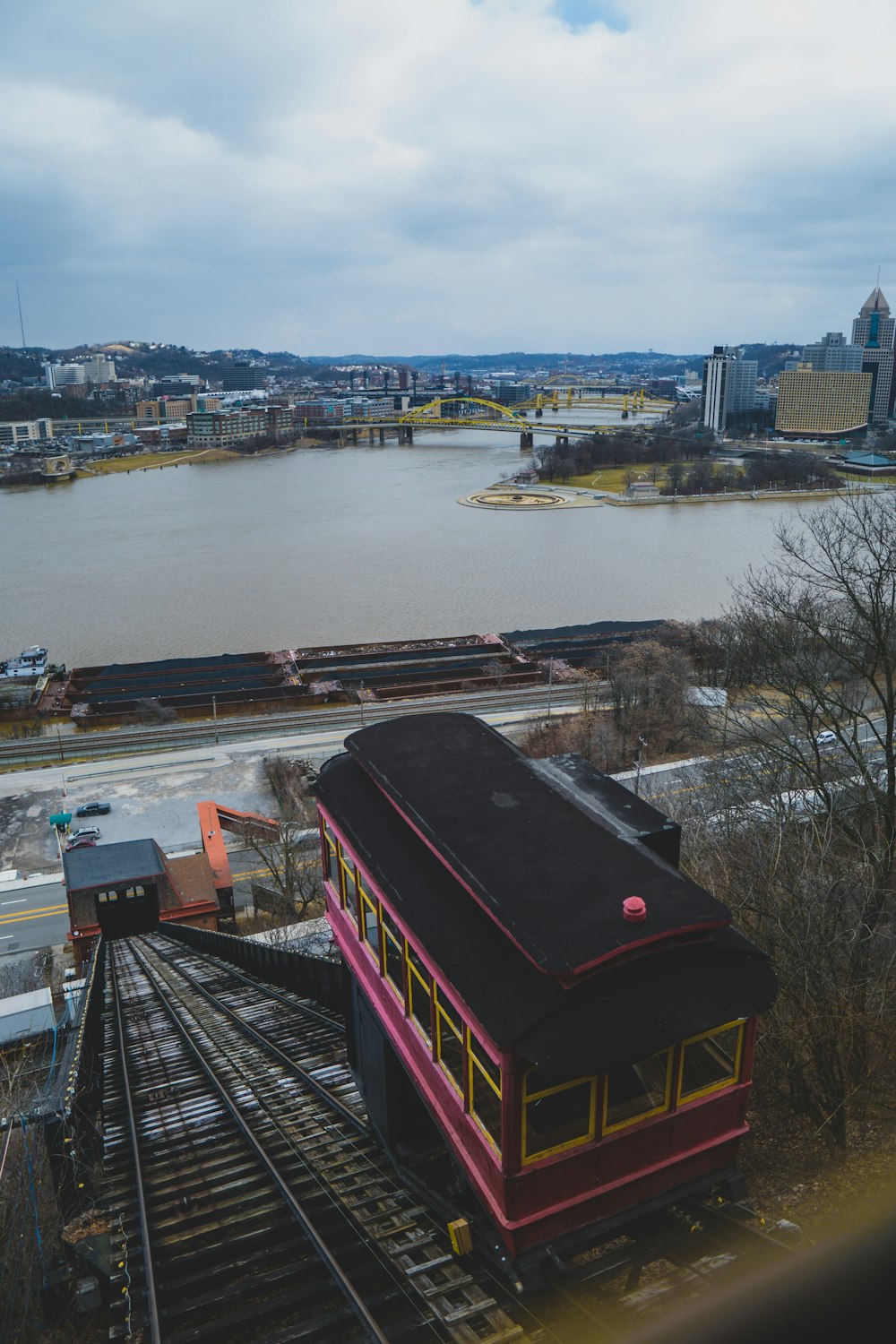 a red and black train traveling down tracks next to a river