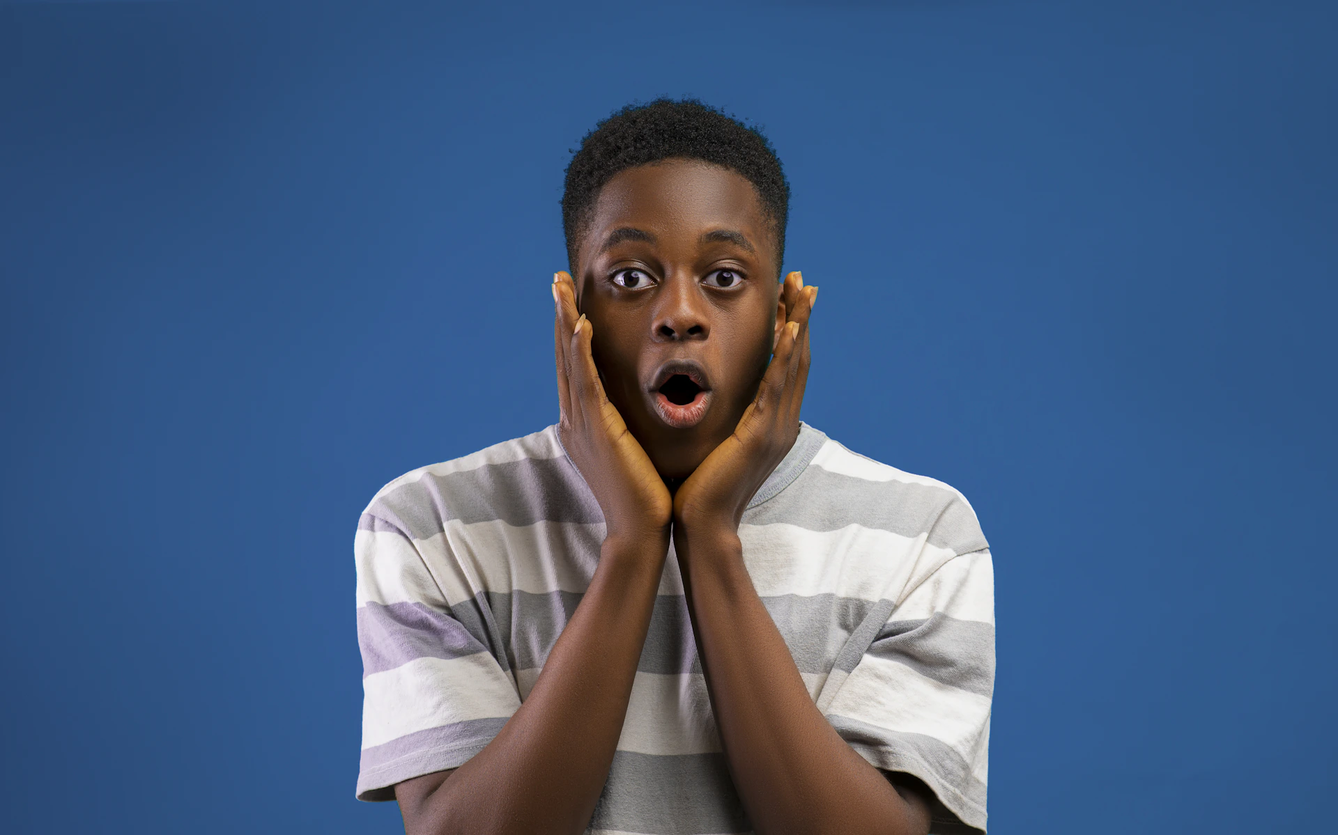 a boy making a surprised face with his hands