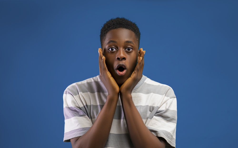 a boy making a surprised face with his hands