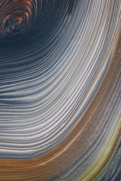 Swirling, concentric patterns create a mesmerizing abstract design, with smooth lines and an interplay of colors forming a vortex-like appearance.