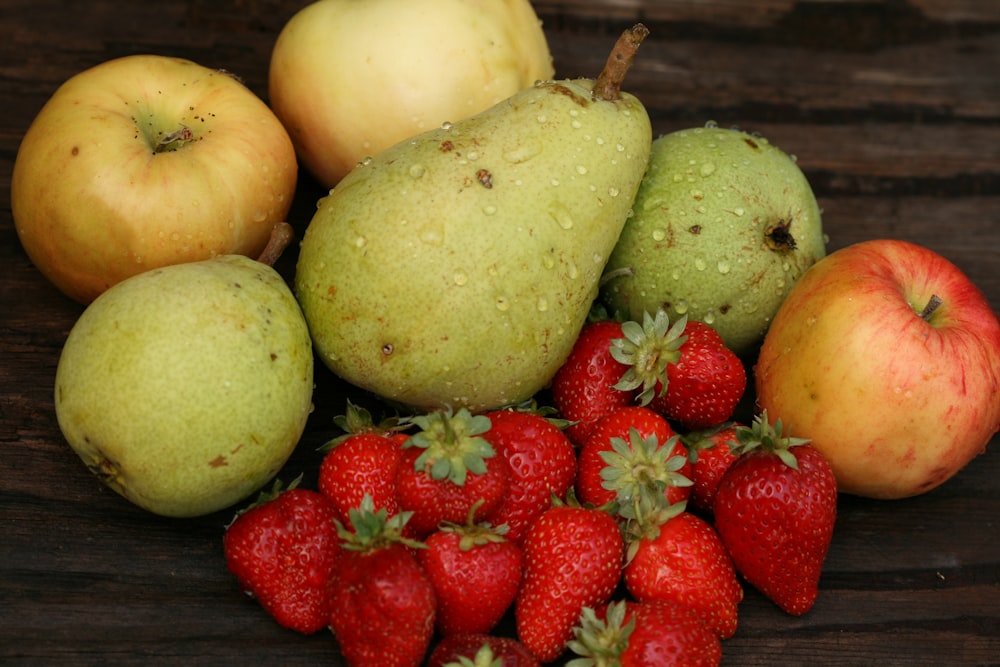 a pile of fruit sitting on top of a wooden table