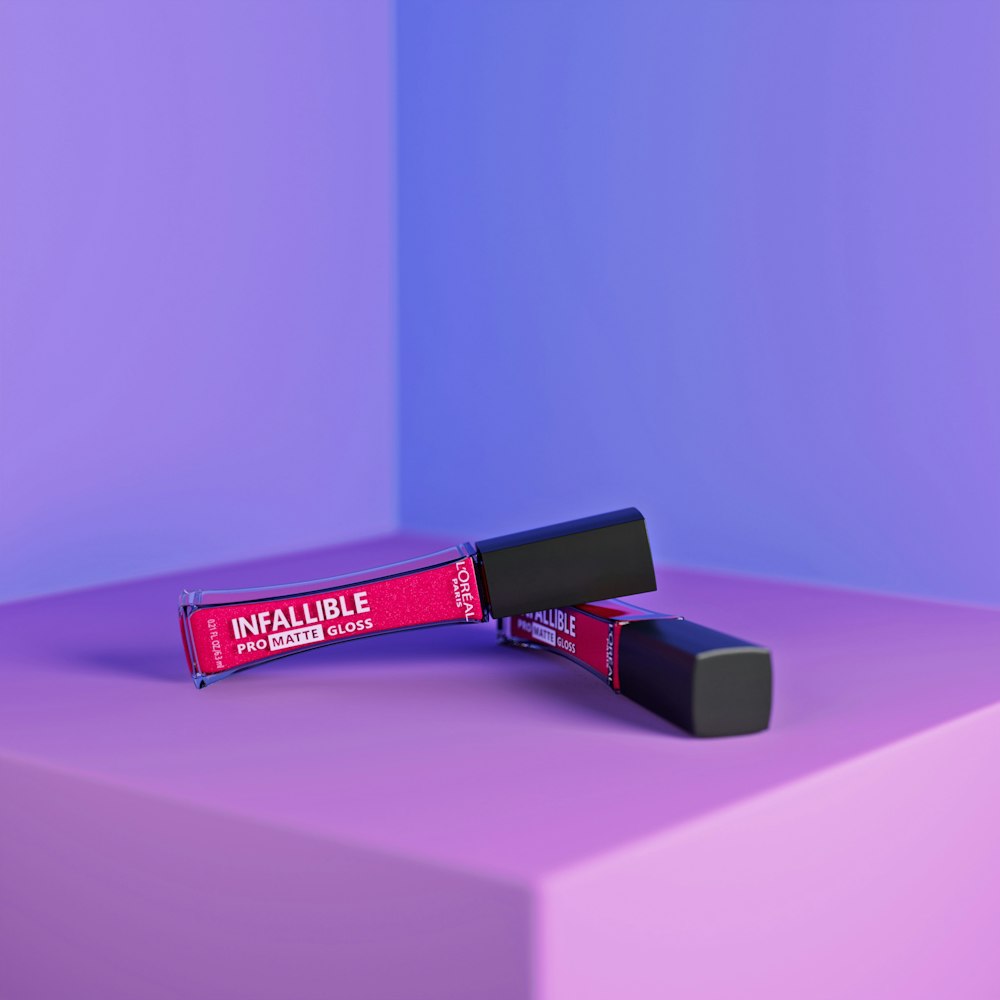 a pink and purple background with a lipstick tube