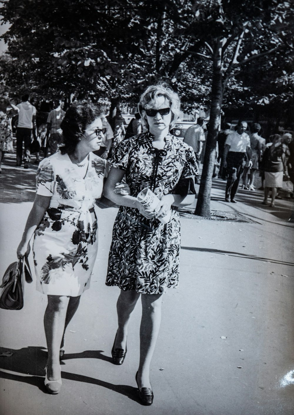 a black and white photo of two women walking down a street