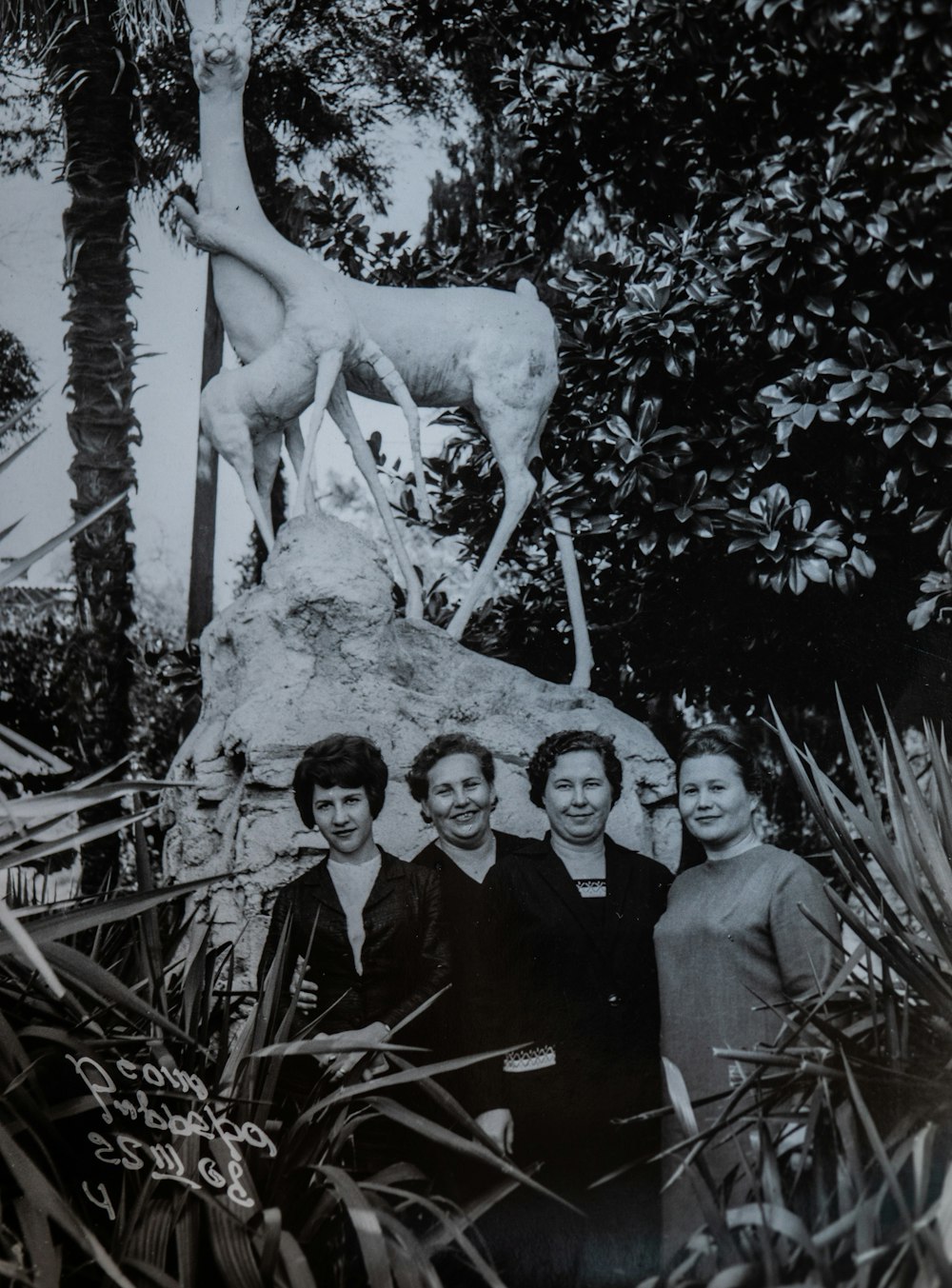 a group of people standing next to a statue of a giraffe