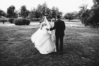 a bride and groom walking through a field