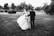 a bride and groom walking through a field