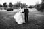 a bride and groom walking through a field