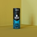 A can of deodorant, labeled BOLD, stands upright against a yellow background. The bottle features a sleek black design with blue geometric patterns and the word ALPHA written on it.