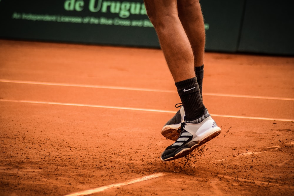 os pés e sapatos de um tenista em uma quadra de saibro