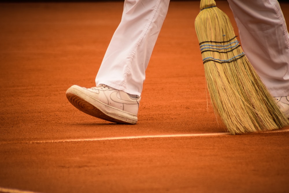 a person standing on a tennis court holding a broom