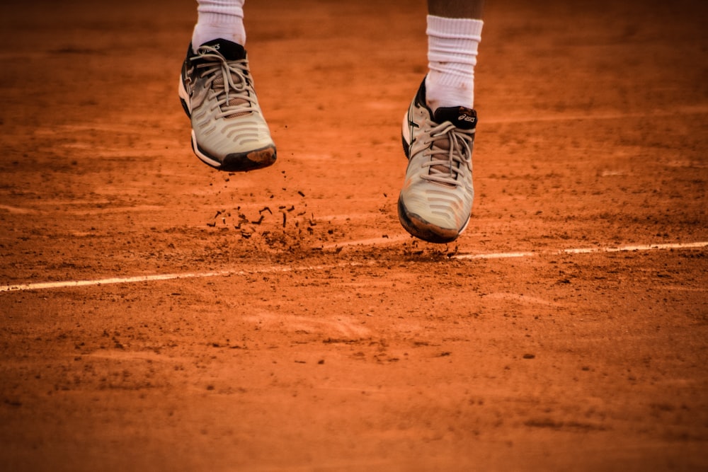 os pés e sapatos de um tenista em uma quadra de saibro