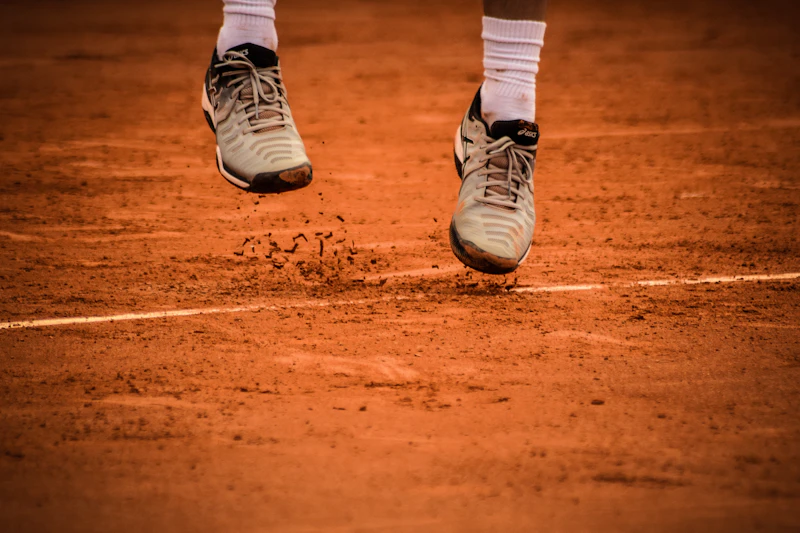 A tennis player's shoes on red clay