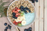 Healthy breakfast bowl topped with peanut butter, fresh fruits, and seeds.