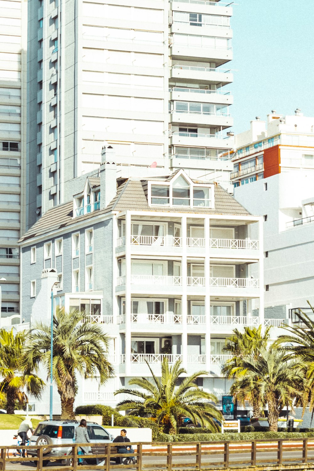 a white building with balconies and palm trees in front of it