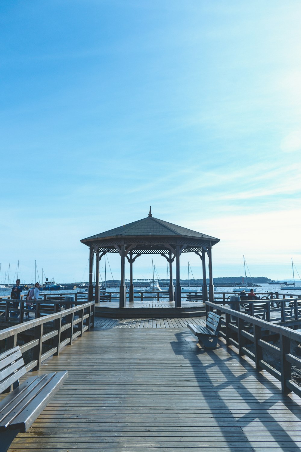 a wooden pier with benches and a gazebo