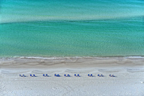 A tranquil beach scene with crystal-clear water and sun loungers arranged neatly.