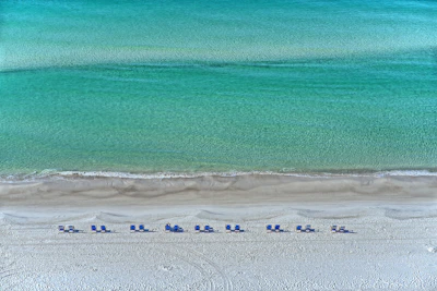 A serene turquoise beach with gentle waves and a minimalist luxury lounge setup.