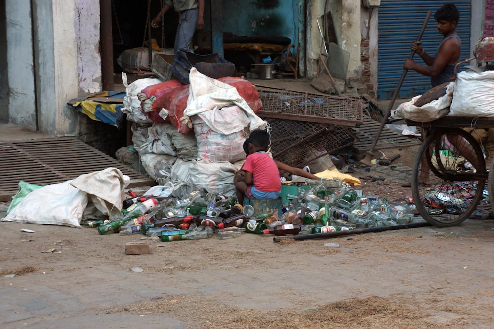 a woman sitting on the ground next to a pile of bottles