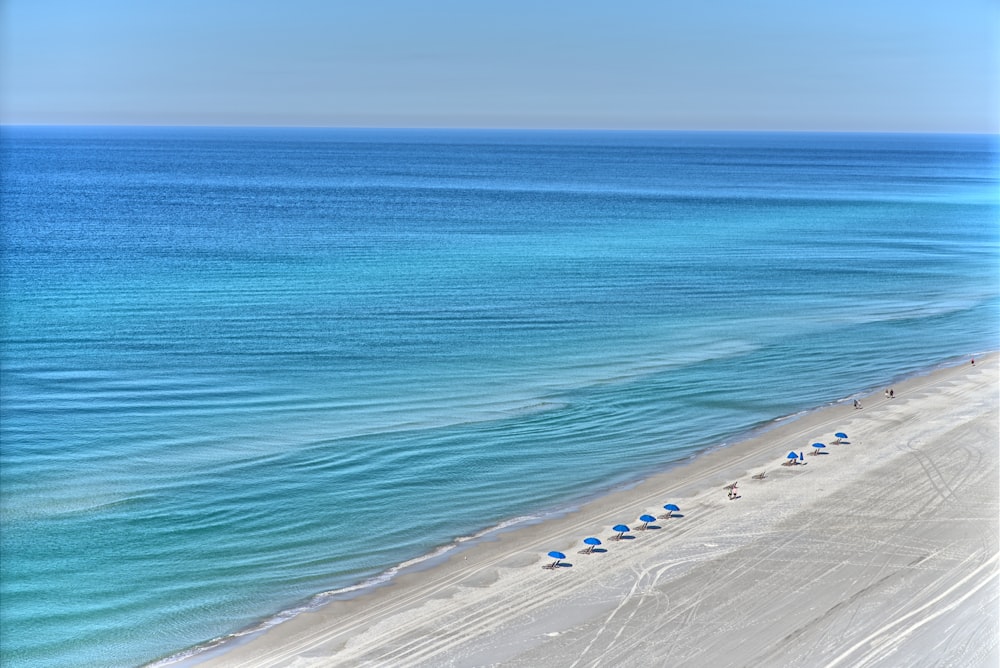 an aerial view of a beach with umbrellas and blue water