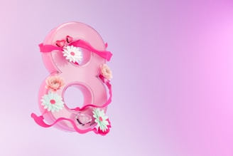 a pink number eight decorated with flowers and ribbons