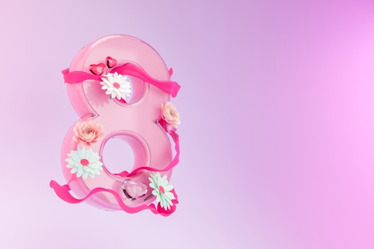 a pink number eight decorated with flowers and ribbons