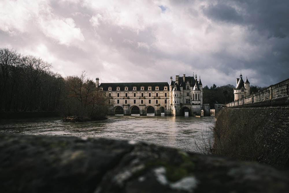 a large building sitting next to a river under a cloudy sky