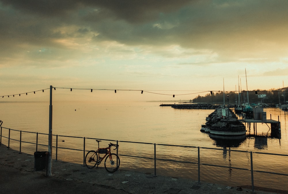 a bike parked next to a fence near a body of water