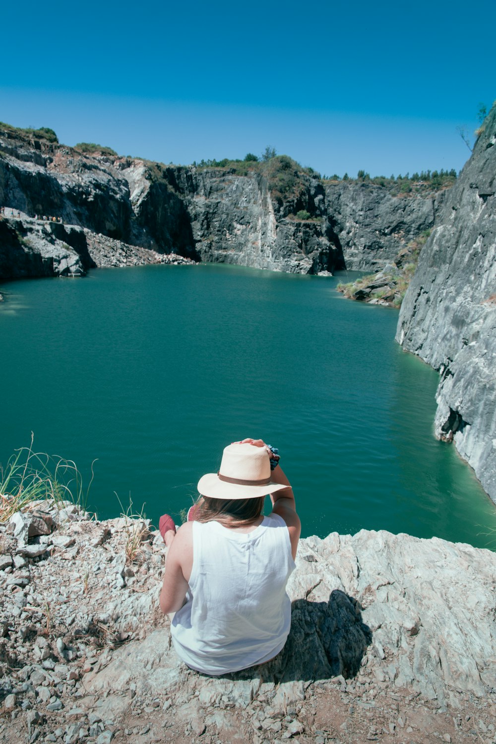 a person sitting on a rock looking at a lake