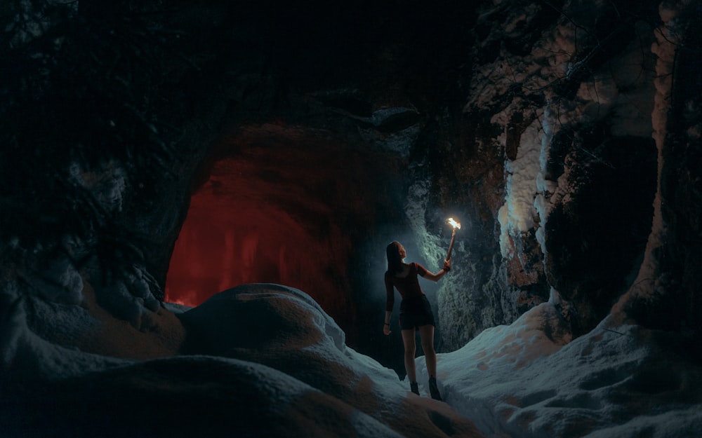 a woman standing in a cave holding a flashlight