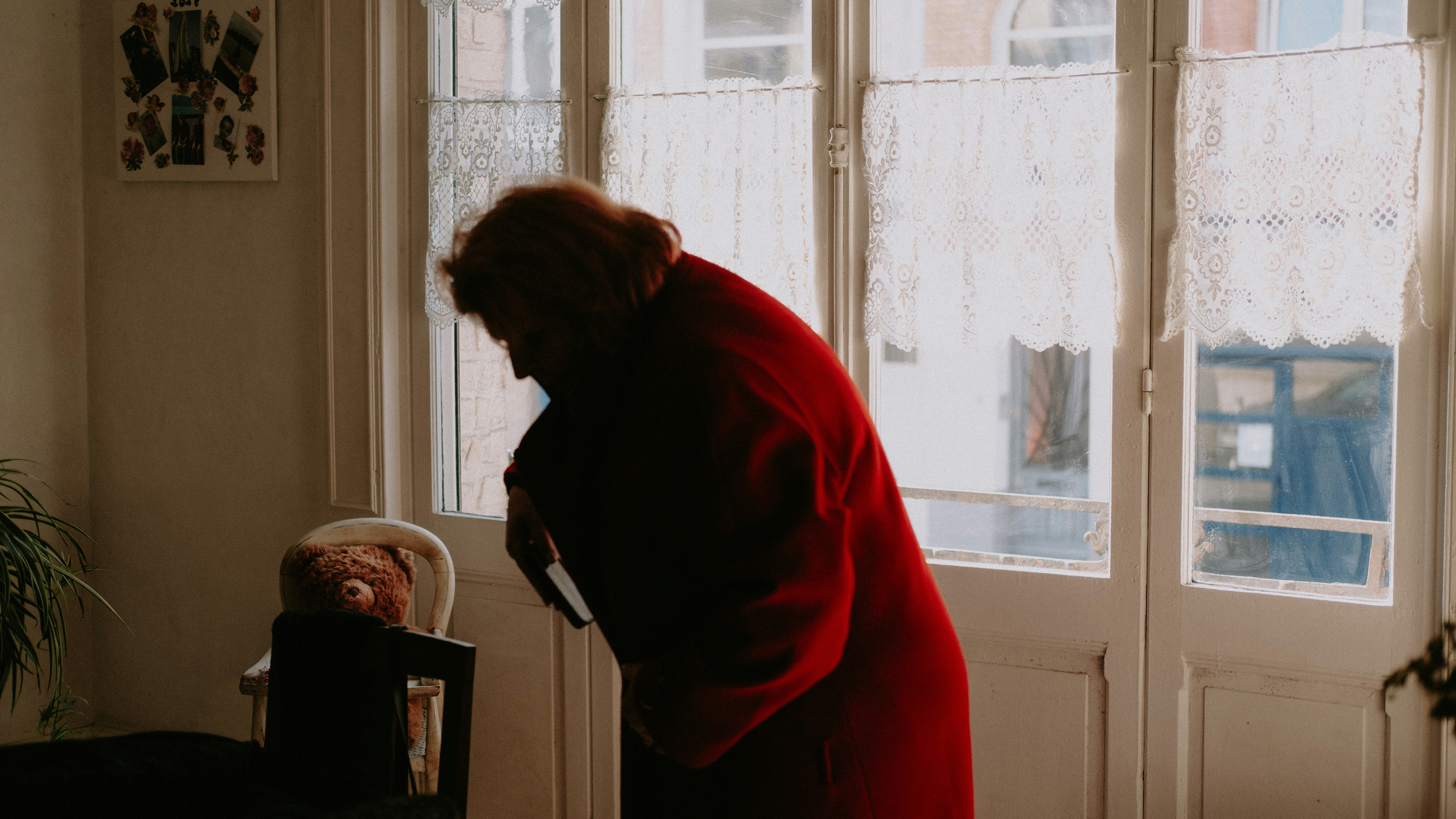 a woman in a red coat looking at a teddy bear