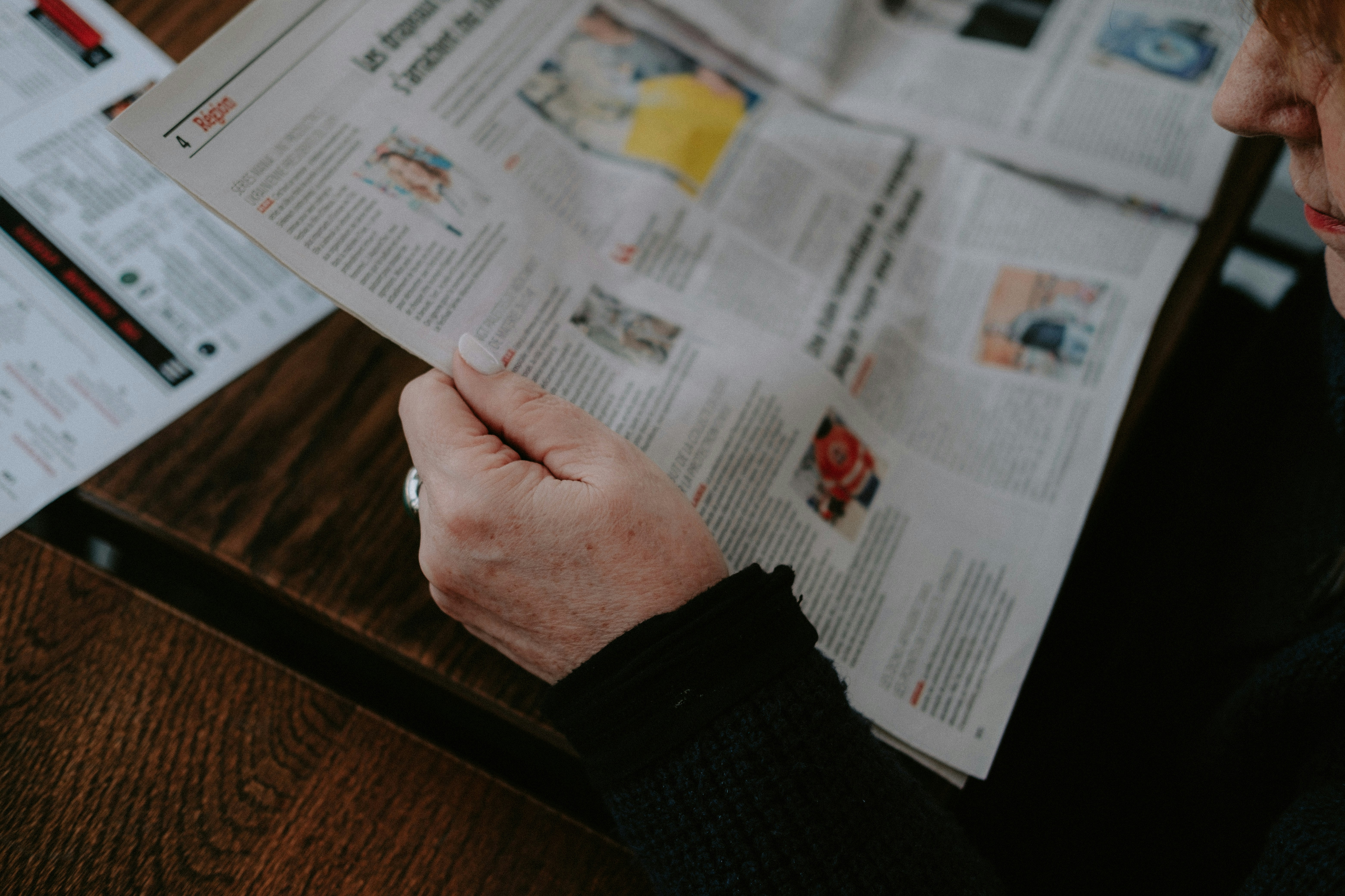 a person sitting at a table reading a newspaper