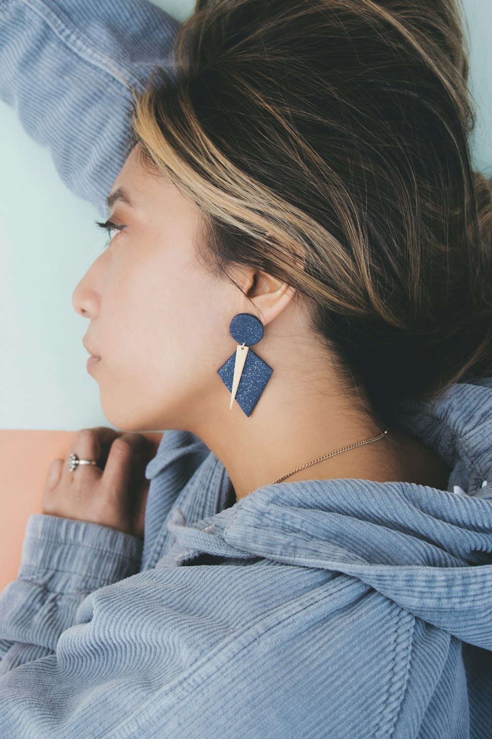 a woman wearing a blue shirt and a pair of earrings