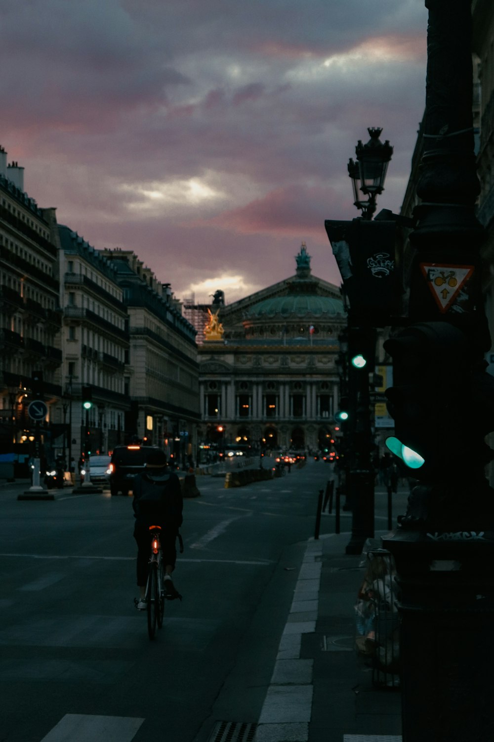 a man riding a bike down a street next to tall buildings