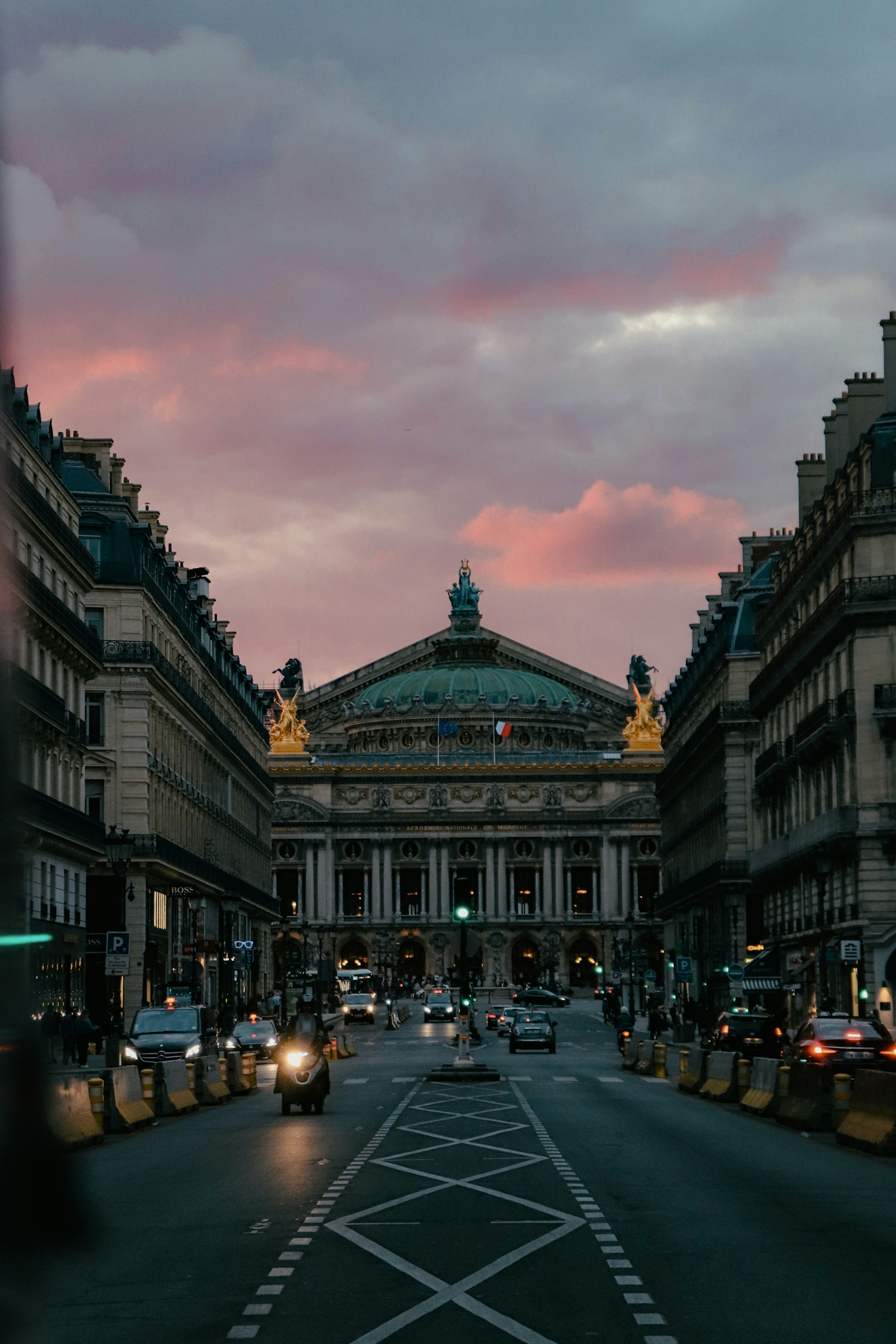 a city street at dusk with a building in the background