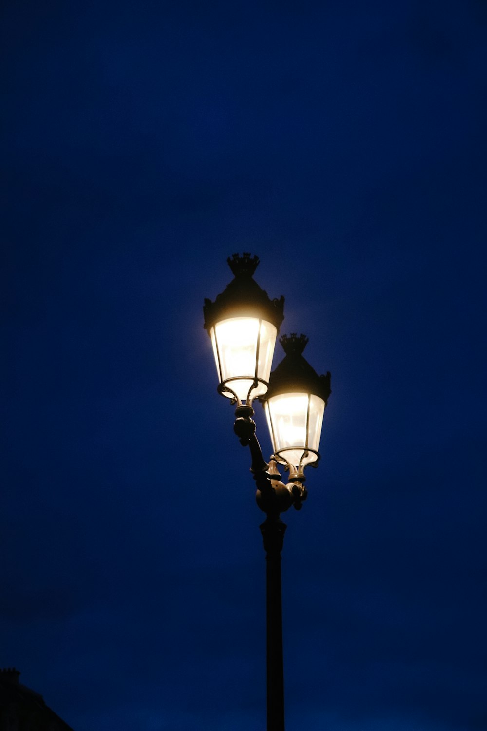 a street lamp lit up against a dark blue sky