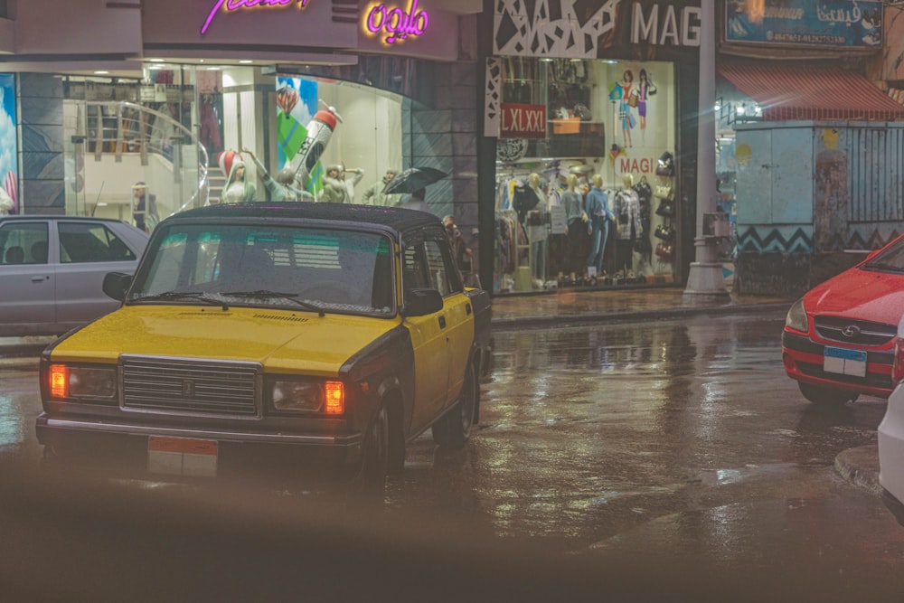 a yellow taxi cab driving down a rain soaked street