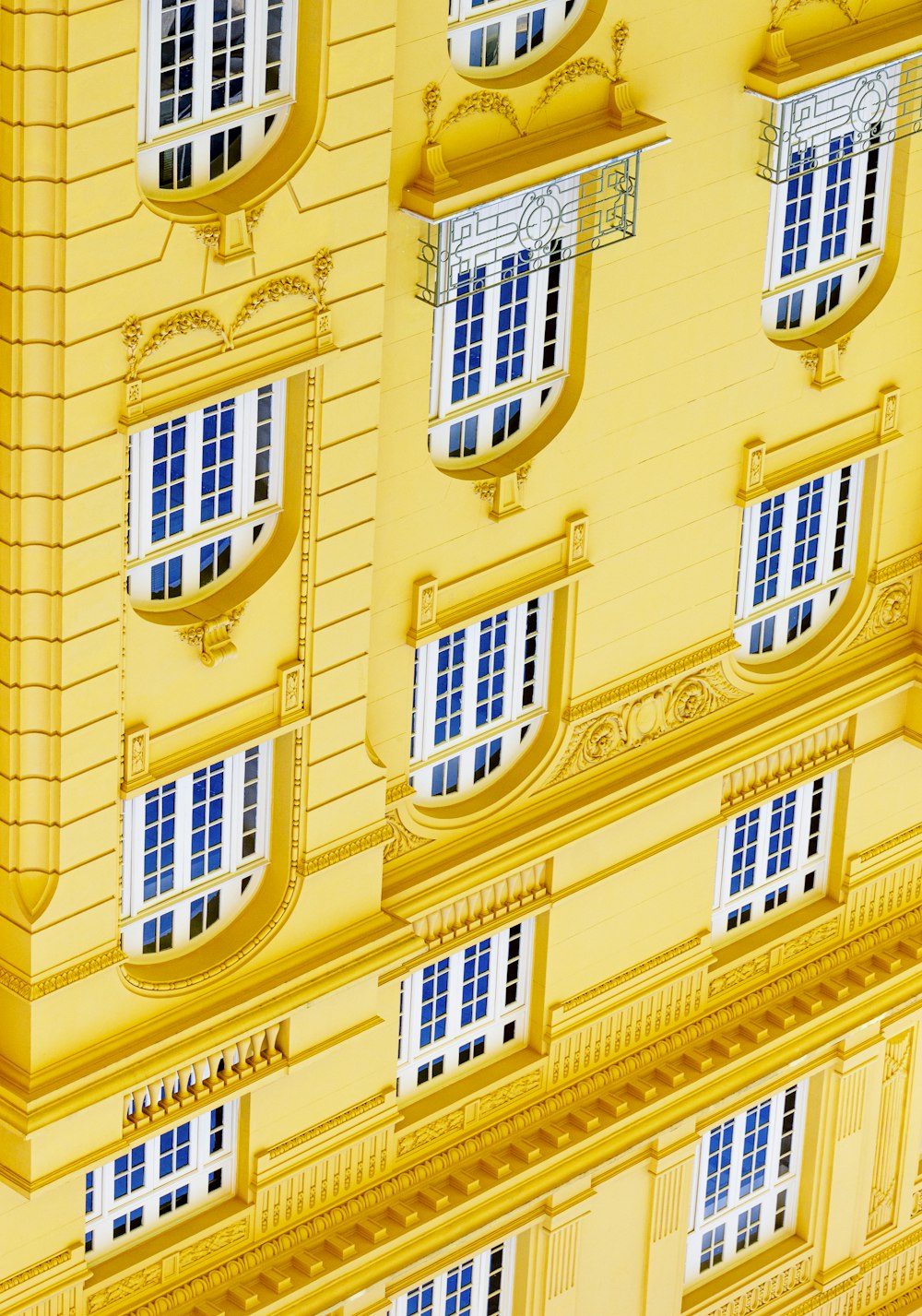 a yellow building with white windows and blue shutters