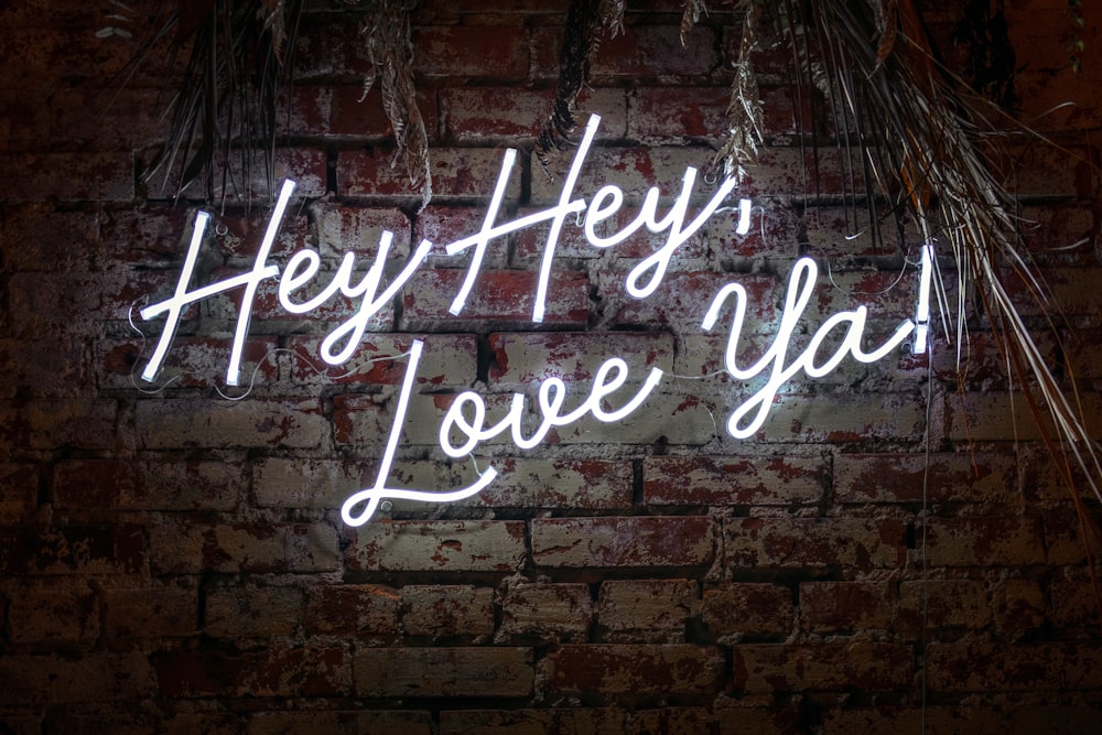 Un muro di mattoni con un'insegna al neon che dice hey hey love you