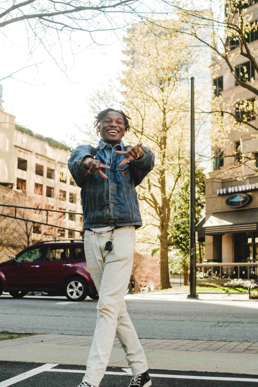 a man standing on a street corner with his hands in the air