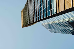 A sleek commercial glass curtain wall reflecting the London skyline on a sunny day.